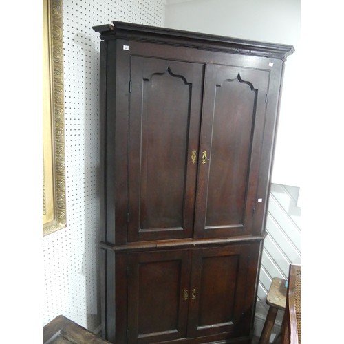 451 - A 19thC oak Corner Cupboard, panelled doors opening to reveal three shaped shelves, above brush slid... 