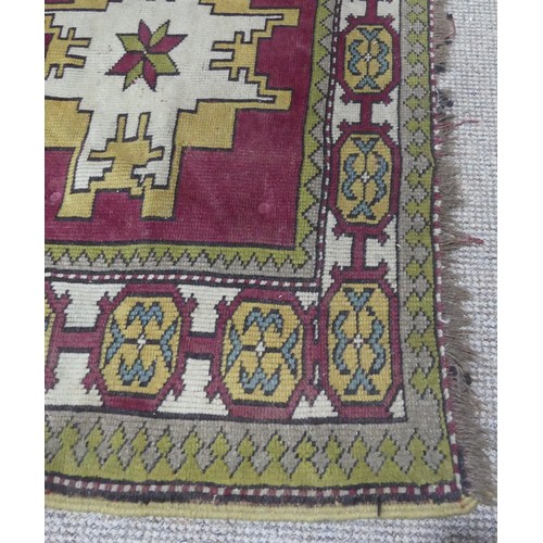 490 - Tribal rugs; a Turkish Rug, hand-knotted with ochre geometric designs on a plum ground, worn, 115cm ... 