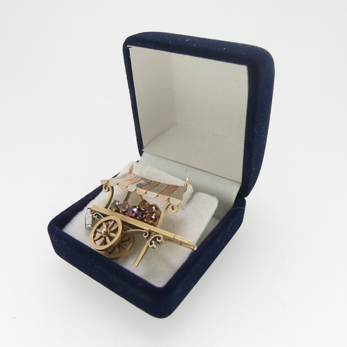 113 - A charming 9ct tri-colour gold Brooch, in the form of a hand cart, with rotating wheels, set with ha... 