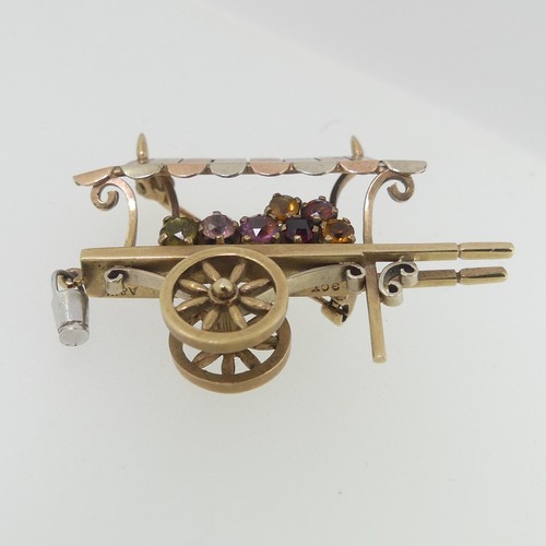 113 - A charming 9ct tri-colour gold Brooch, in the form of a hand cart, with rotating wheels, set with ha... 