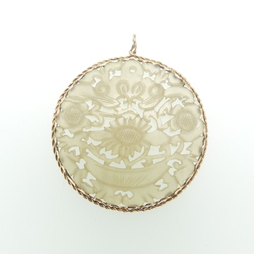 74 - A circular pierced Jade Pendant, with foliate decoration, in an unmarked ropetwist mount, tested as ... 