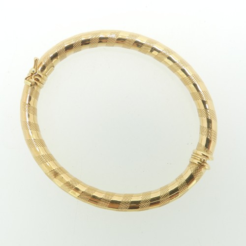 103 - An 18ct yellow gold hinged hollow Bangle, by Uno-a-Erre, with alternate bands of textured and polish... 