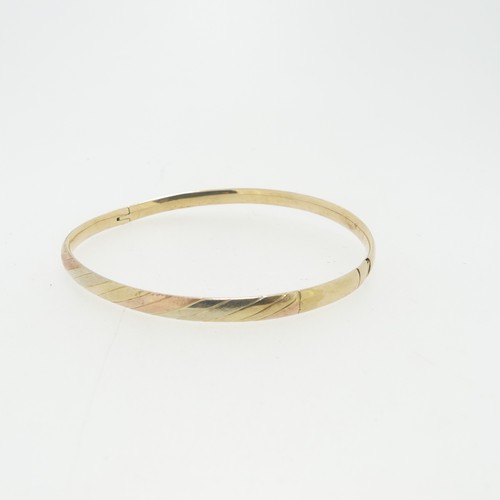 104 - A narrow hollow hinged Bangle, the front with bands of tri-colour gold, unmarked, tested as 9ct, cla... 