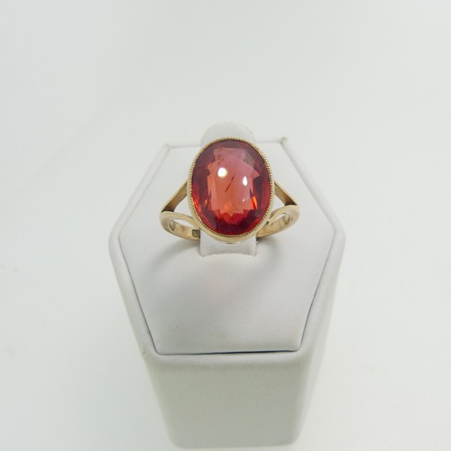 61 - A 9ct yellow gold Ring, set with an oval facetted red stone, possibly ruby, 11.8mm x 9.3mm, millegra... 