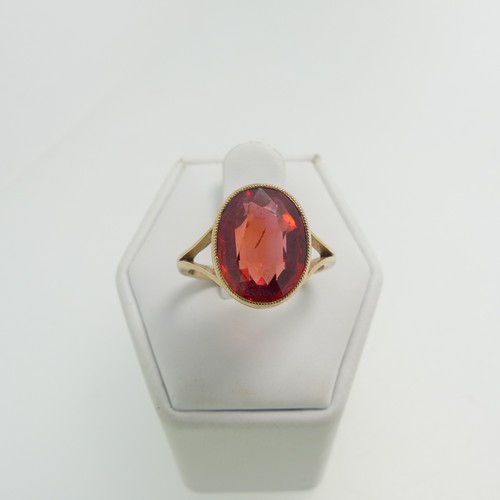 61 - A 9ct yellow gold Ring, set with an oval facetted red stone, possibly ruby, 11.8mm x 9.3mm, millegra... 