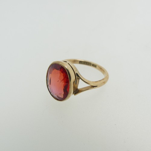 61 - A 9ct yellow gold Ring, set with an oval facetted red stone, possibly ruby, 11.8mm x 9.3mm, millegra... 