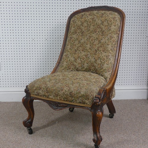 254 - A Victorian carved upholstered nursing chair, with floral carved press rail upon cabriole legs and s... 