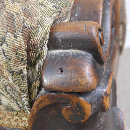 254 - A Victorian carved upholstered nursing chair, with floral carved press rail upon cabriole legs and s... 