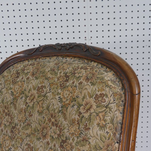 254 - A Victorian carved upholstered nursing chair, with floral carved press rail upon cabriole legs and s... 