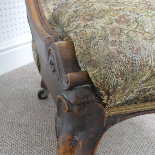 254 - A Victorian carved upholstered nursing chair, with floral carved press rail upon cabriole legs and s... 