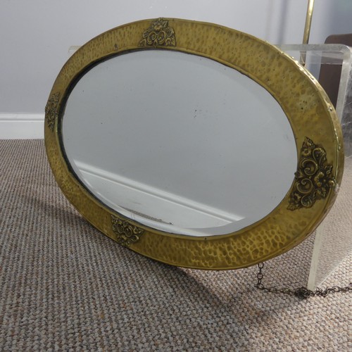 270 - An Arts & Crafts oval brass mirror with decorative overlay to four of its edges, has it's origin... 