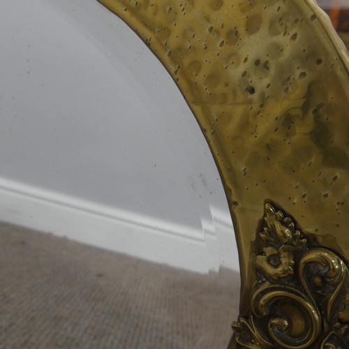 270 - An Arts & Crafts oval brass mirror with decorative overlay to four of its edges, has it's origin... 