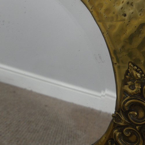 270 - An Arts & Crafts oval brass mirror with decorative overlay to four of its edges, has it's origin... 