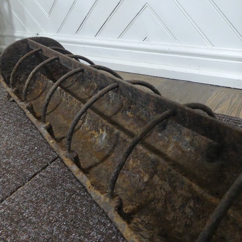 407 - An antique cast iron pig feeder, W 95 cm x H 18 cm x D 25 cm.