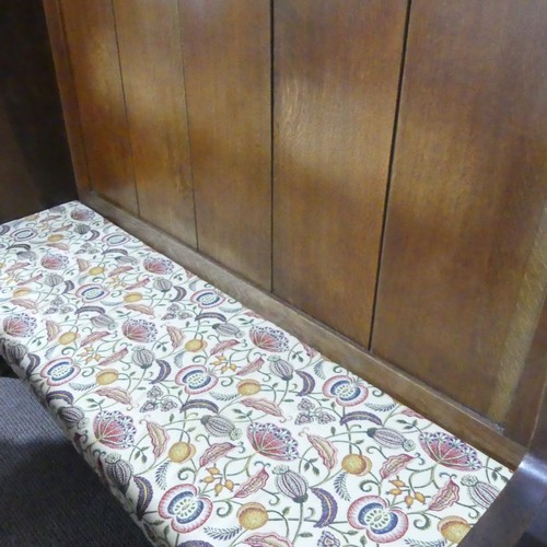 384 - An early 20thC oak Settle, with a floral upholstered removable seat cover, W 136.6 cm x H 126 cm x D... 