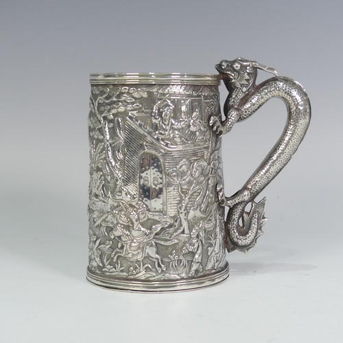 A mid-19thC Chinese Export silver Mug, marked KHC, for Khecheong of Canton, of conical form, with a continuous scene decoration in low relief depicting a procession towards a fortress, with scrolling dragon handle, cartouche with presentation inscription dated 1864, 12cm high, approx weight 10.1ozt.