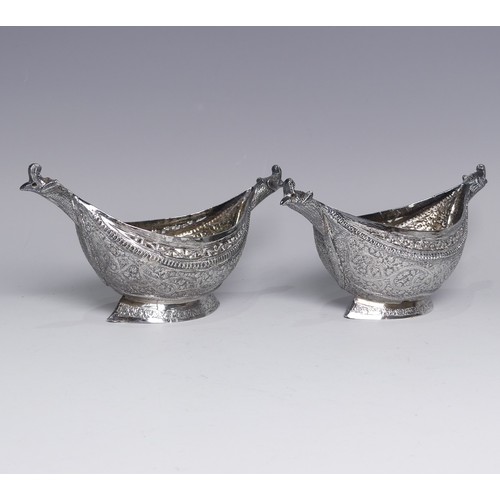 136 - A pair of antique Indian silver boat-shaped Dishes, with bird head handles, pierced rims and chased ... 