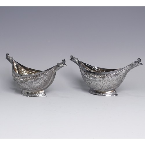 136 - A pair of antique Indian silver boat-shaped Dishes, with bird head handles, pierced rims and chased ... 