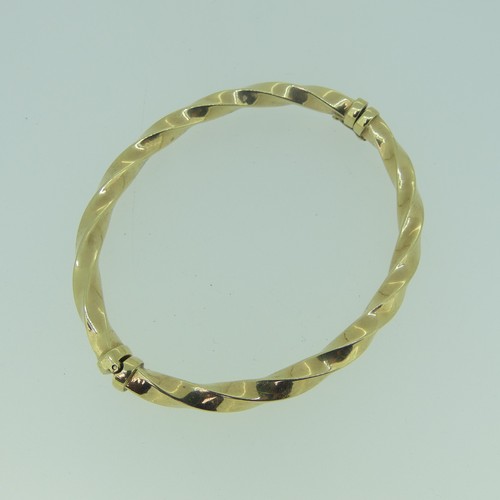 407 - A 9ct yellow gold hollow hinged Bangle, swirl fluted, 7.9g.