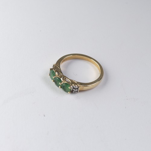 343 - A three stone emerald Ring, the circular facetted stones approx 4.4mm diameter, with two diamond poi... 