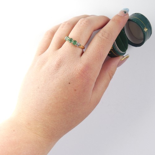 343 - A three stone emerald Ring, the circular facetted stones approx 4.4mm diameter, with two diamond poi... 