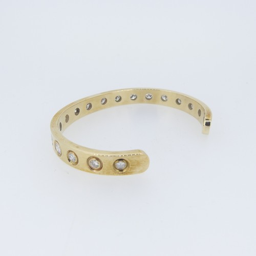 406 - A diamond Cuff Bracelet, the plain C shaped band set with eighteen graduated circular diamonds, each... 