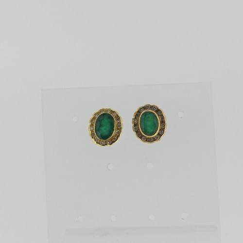 447 - A pair of emerald and diamond cluster Earrings, the central oval emerald approx. 7mm long, collet se... 