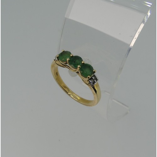 343 - A three stone emerald Ring, the circular facetted stones approx 4.4mm diameter, with two diamond poi... 