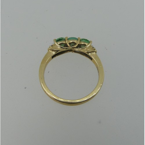 343 - A three stone emerald Ring, the circular facetted stones approx 4.4mm diameter, with two diamond poi... 