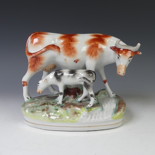 40 - An antique Staffordshire pottery group of a Cow with its Calf, raised on moulded plinth, together wi... 