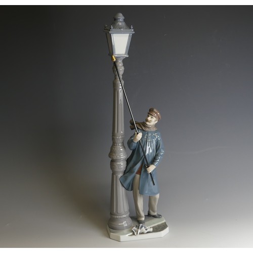 207 - A Lladro porcelain model of a Lamplighter, modelled with figure holding a torch toward the lamp, H 4... 