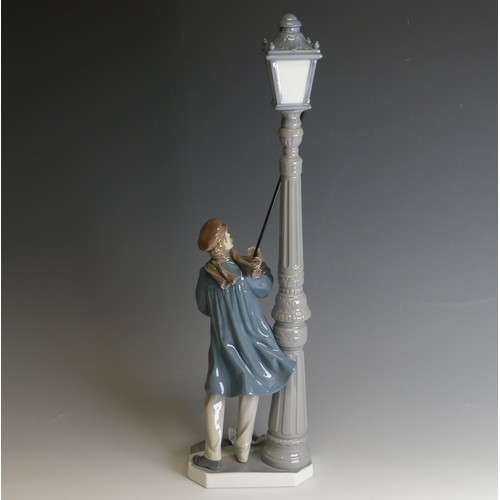 207 - A Lladro porcelain model of a Lamplighter, modelled with figure holding a torch toward the lamp, H 4... 