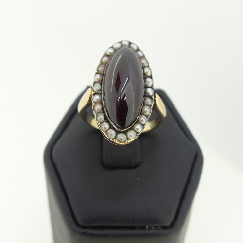 103 - An early 19thC garnet and seed pearl cluster Ring, the oval cabochon garnet 20mm long, with seed pea... 