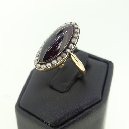 103 - An early 19thC garnet and seed pearl cluster Ring, the oval cabochon garnet 20mm long, with seed pea... 