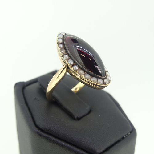 103 - An early 19thC garnet and seed pearl cluster Ring, the oval cabochon garnet 20mm long, with seed pea... 