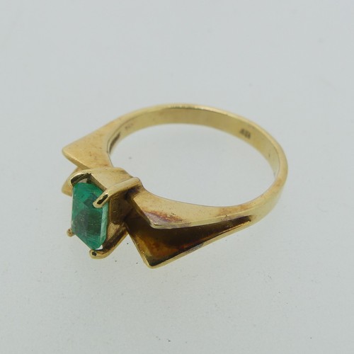 107 - A small emerald Ring, the emerald cut stone 5.9mm long, four claw set in a modernist 18ct gold shank... 