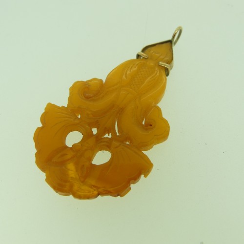 237 - A gold mounted carved amber 'Star' Pendant, 4cm wide, unmarked, tests as 9ct, in accompanying box an... 