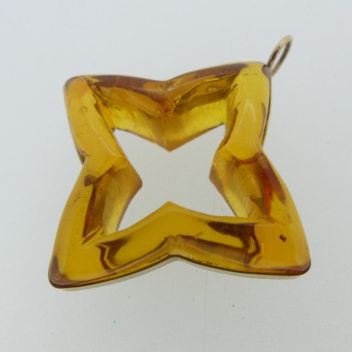 237 - A gold mounted carved amber 'Star' Pendant, 4cm wide, unmarked, tests as 9ct, in accompanying box an... 