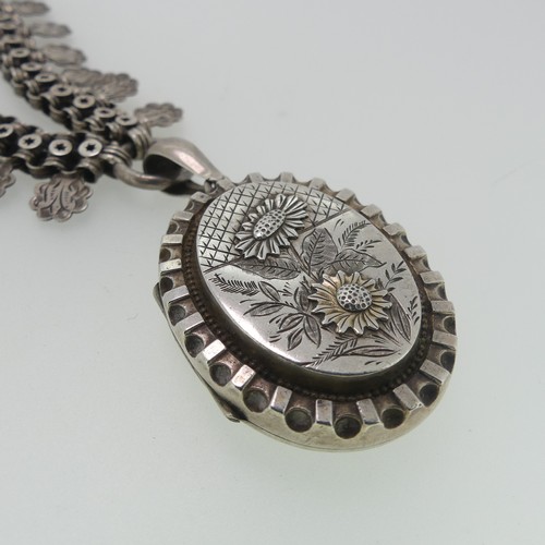 162 - A Victorian silver Locket and Chain, in the Aesthetic style, the oval hinged locket with foliate dec... 