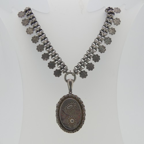 162 - A Victorian silver Locket and Chain, in the Aesthetic style, the oval hinged locket with foliate dec... 