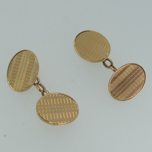 261 - A pair of 15ct yellow gold oval Cufflinks, with engine turned decoration, chain between, 6.4g.... 