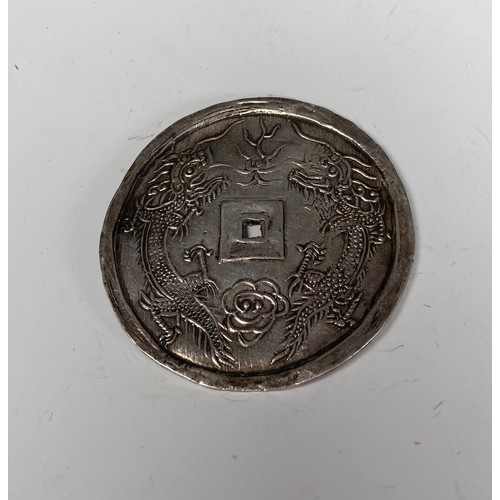 352 - A 19thC Asian silver Coin, one side with four character marks, the other with two stylised dragons, ... 