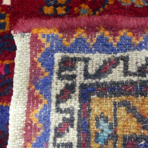 604 - Tribal Rugs; a Persian Qashqai Rug, red ground, thick wool pile on cotton base, worn along one edge,... 