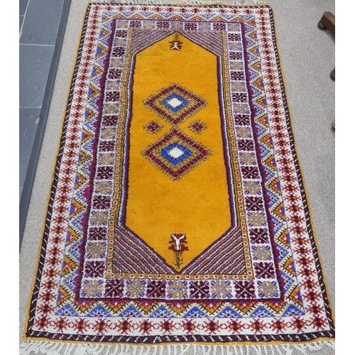 611 - Tribal Rugs; a vintage yellow ground Rug, possibly Moroccan, with two central medallions and wide br... 