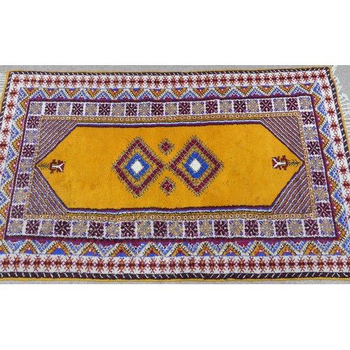 611 - Tribal Rugs; a vintage yellow ground Rug, possibly Moroccan, with two central medallions and wide br... 