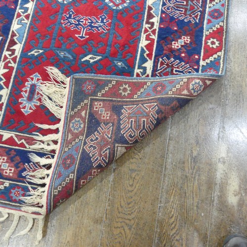 616 - Tribal Rugs; a Turkish Rug, blue and red ground with all over geometric pattern set within a wide bo... 