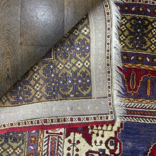 617 - Tribal Rugs; an old Turkish Yahyali Rug, blue and red ground with cream central medallion, within a ... 