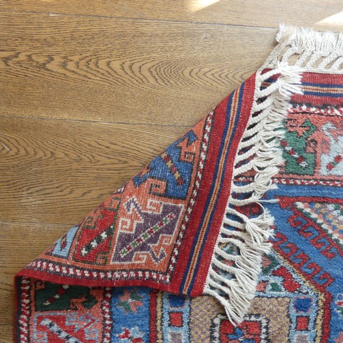 609 - Tribal Rugs; a blue ground Caucasian Runner, the whole with typical geometric patterns in bright col... 