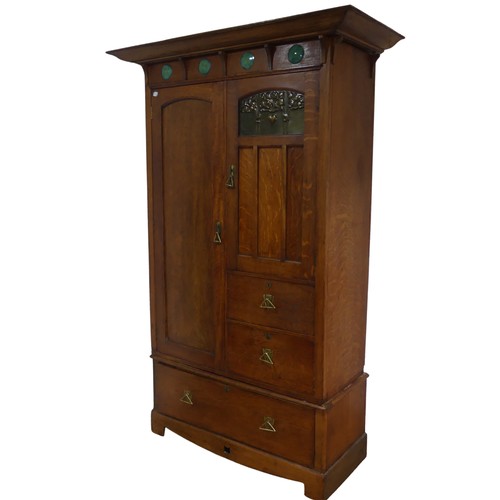 A Shapland and Petter of Barnstaple, Arts and Crafts oak Wardrobe, circa 1900, the projecting cornice above a frieze of four Ruskin roundels above one long door, the opposing door with embossed metal panel, above two short drawers, the whole above one long drawer, lock stamped S&P/ B, W 136 cm x H 207 cm x D 59 cm. Provenance: property of a West Country Collector. After buying an Arts & Crafts house, the vendors researched and sought-out beautiful, often unique, Arts & Crafts pieces to furnish their home.