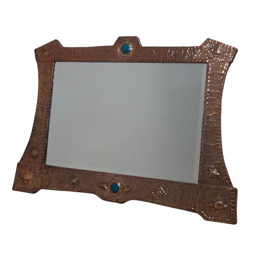 A large Arts and Crafts Copper Wall Mirror, with shaped hammered frame decorated in embossed stars and set with two ruskin pottery roundles to top and bottom, encasing bevelled glass plate, W 96.5 cm x H 66 cm. Provenance: property of a West Country Collector. After buying an Arts & Crafts house, the vendors researched and sought-out beautiful, often unique, Arts & Crafts pieces to furnish their home.